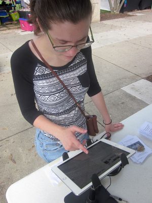 Roanoke College Work-Study Research Assistant Haleigh Ardolino tests out the technology for presentation of a digital exhibition at the Southwest Virginia LGBTQ+ History Project's booth at the Pride in the Park festival, September 11, 2016. Photo credit: Photograph by the author.
