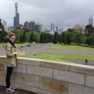 The author stands on the steps of the Shrine of Remembrance, with the Melbourne skyline in the background.
