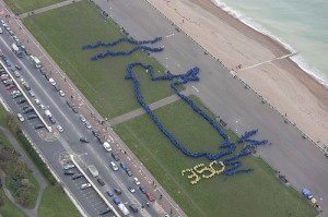 As part of a 2010 "planetary art show" organized by 350.org, people in Brighton-Hove, UK formed a giant image of King Canute, who famously tried to control the rising ocean.  Photo credit:  Malcolm Land. 