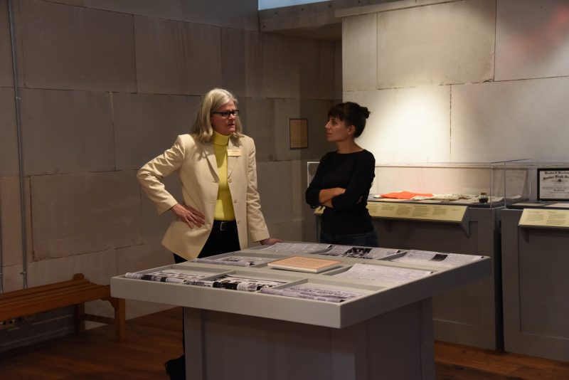 Public historians Jennifer Dickey and Julia Brock stand beside artifact cases and a vinyl newspaper "touch table" at the opening of Georgia Journeys. Photo credit: Kate Daly