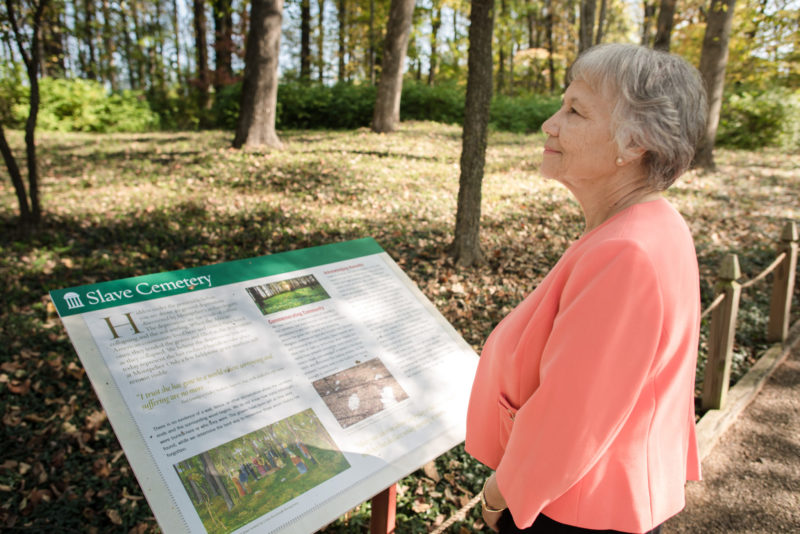 Rebecca Gilmore Coleman, a member of the James Madison's Montpelier Descendant Community, reflecting in front of an interpretive sign for a slave cemetery at James Madison's Montpelier (Photo by Eduardo Montes Bradley, Courtesy of the Montpelier Foundation)