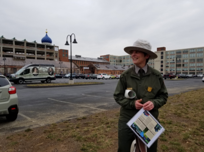 NPS Ranger Amy Glowacki led a tour of Coltsville National Historical Park. The park’s interpretive van sits in the adjacent parking lot. The blue onion dome, first placed by Samuel Colt and reconstructed after a devastating fire soon after his death, marks the manufacturing site. Photo by the author.