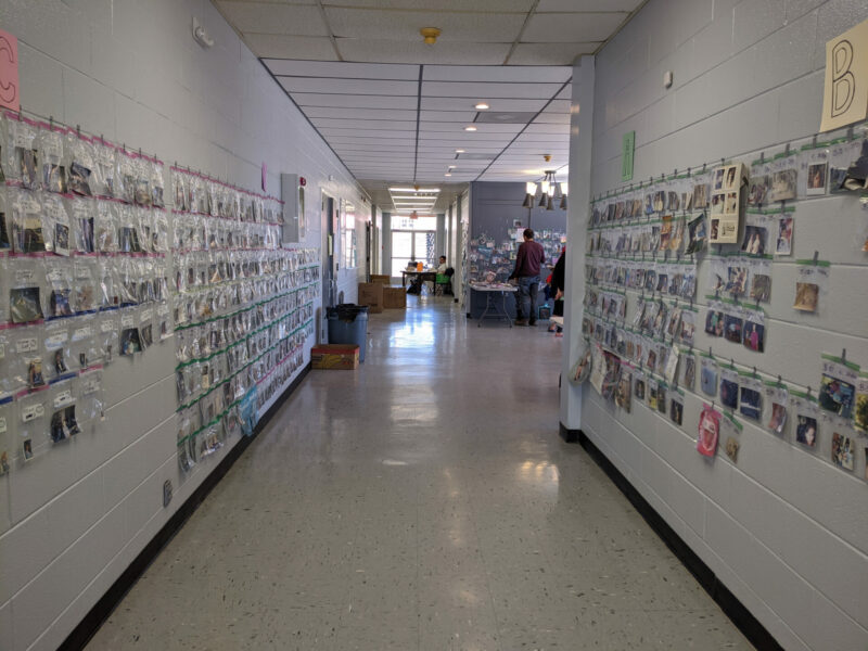 This is a color photograph of a long hallway in the Cookeville Community Center, with bagged photographs and other documents tapped to walls for people to claim.