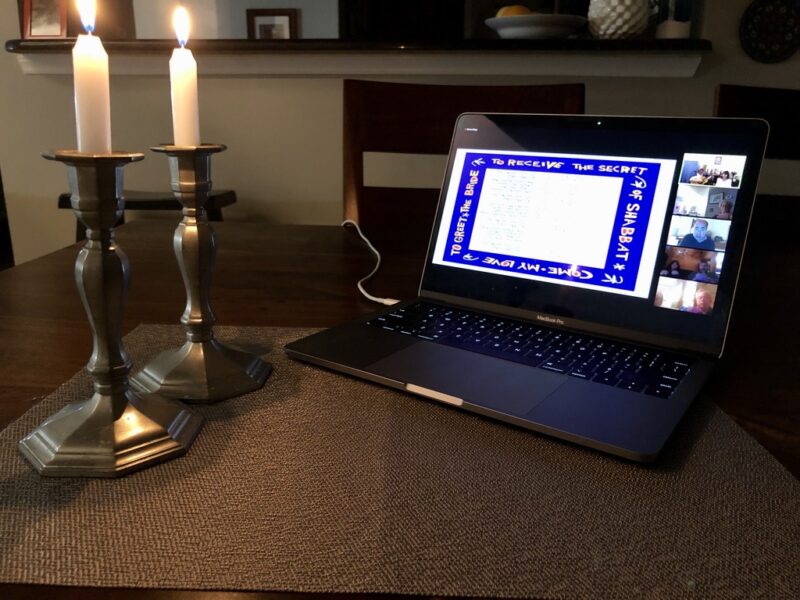 Photo of virtual Shabbat services (a laptop with a Zoom feed accompanied by candles), courtesy of the Capital Jewish Museum.