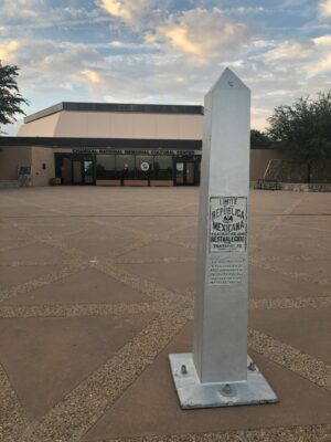 This is a color photograph of an obelisk outside. It reads "LITTLE REPUBLICA MEXICANA" and is in front of a building.