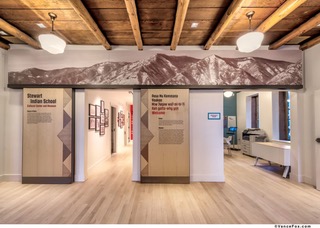Color photograph of a museum lobby featuring labels and mountain graphics on the wall.