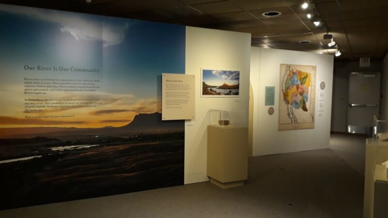 An image of a large exhibition panel depicting a sunset, with a vitrine in front of it. There are other exhibit panels extending to the right.