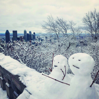 Two snowmen, one smiling and one more ambivalent, reach out for the Montreal skyline from their position atop Mount Royal.”o snowmen, one smiling and one more ambivalent, reach out for the Montreal skyline from their position atop Mount Royal.