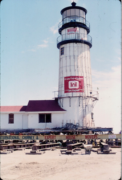 A white lighthouse rests on a complex platform as it is being relocated.