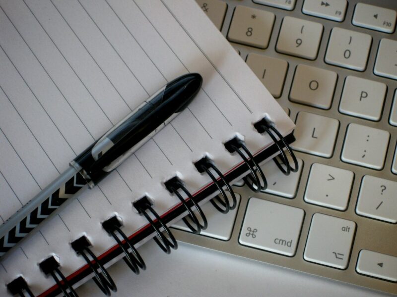 Image of writing tools: pen, paper, and computer keyboard.