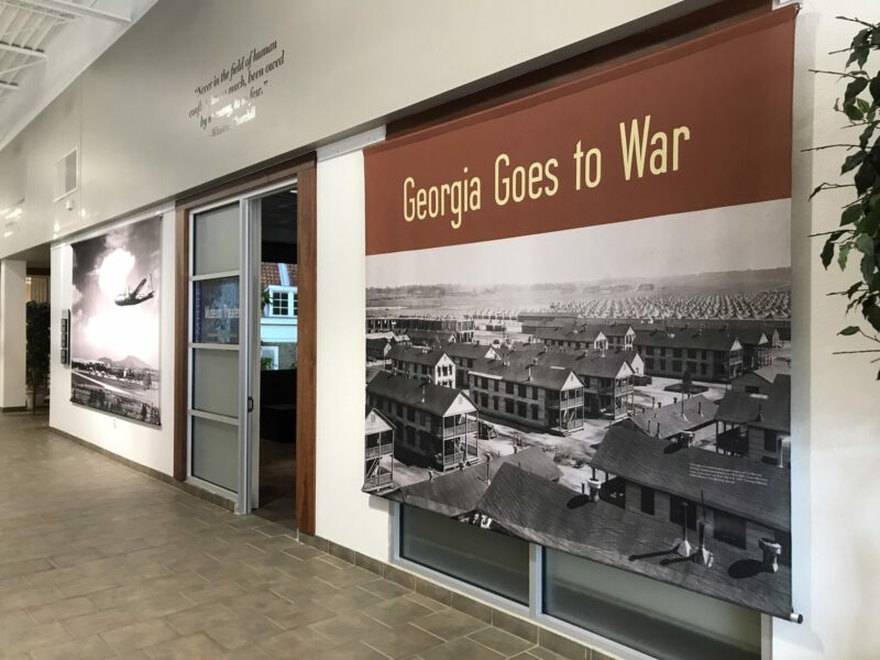 Exhibit panel showing a black and white photograph of rows of houses with the label, "Georgia Goes to War."