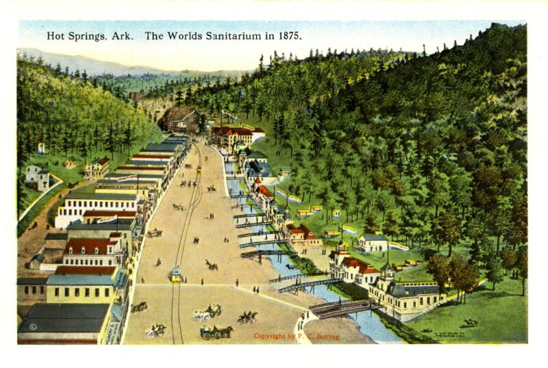 This illustrated postcard depicts a wide road with horse-and-carriage buggies and a streetcar, flanked on one side by several buildings and on the other by a creek. Many small footbridges cross the creek. The buildings, road, and creek are in a valley, sandwiched between two forested hillsides. At the top of the postcard are the following words “Hot Springs, Ark. The Worlds Sanitarium in 1875.”