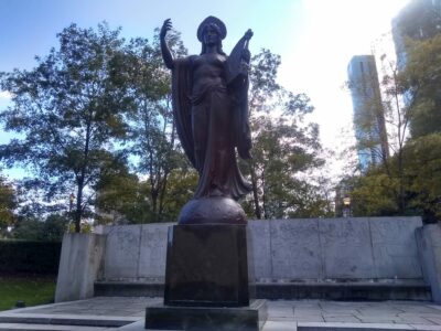 This image depicts a bronze statue of a woman holding a miniature harp.