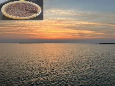 composite image of a pecan pie in the top right corner, overlaid atop a beautiful sunset (or sunrise?) over a lake.