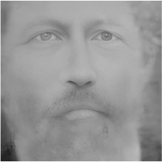 A closely cropped, black and white image of a man. He has a beard and light skin.