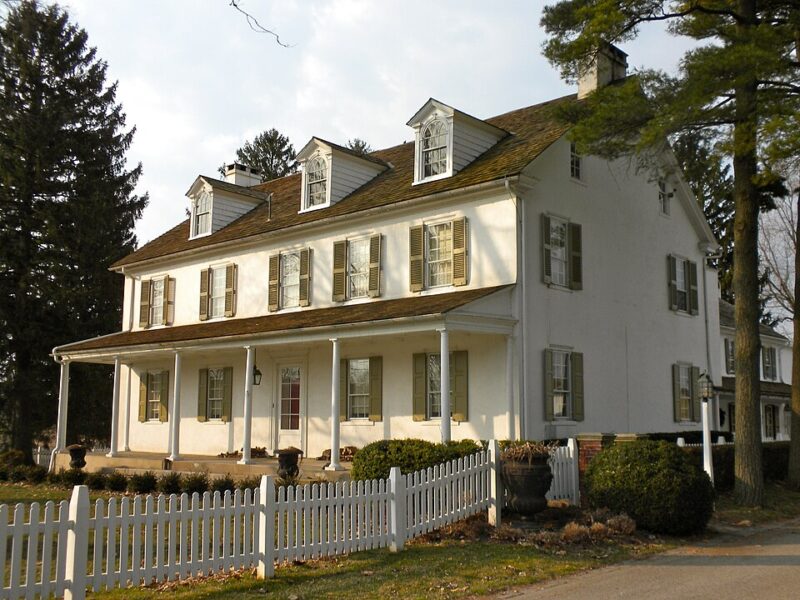 White Chimneys, a large white historic limestone house with multiple brick chimneys, stands behind a split-rail fence and grassy lawn along U.S. Route 30 in Salisbury Township, Lancaster County, Pennsylvania.